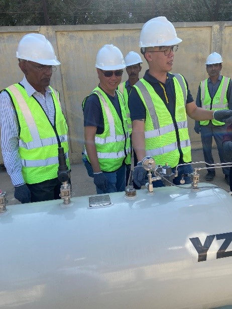 A group of men wearing safety vests and safety hard hats standing next to yz odorizer